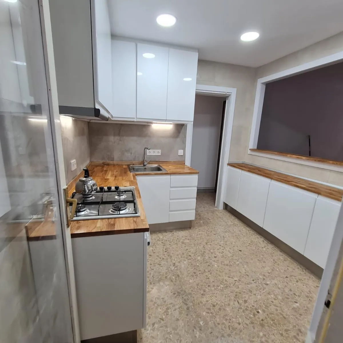 Cocina en L con frentes blancos y encimera de madera